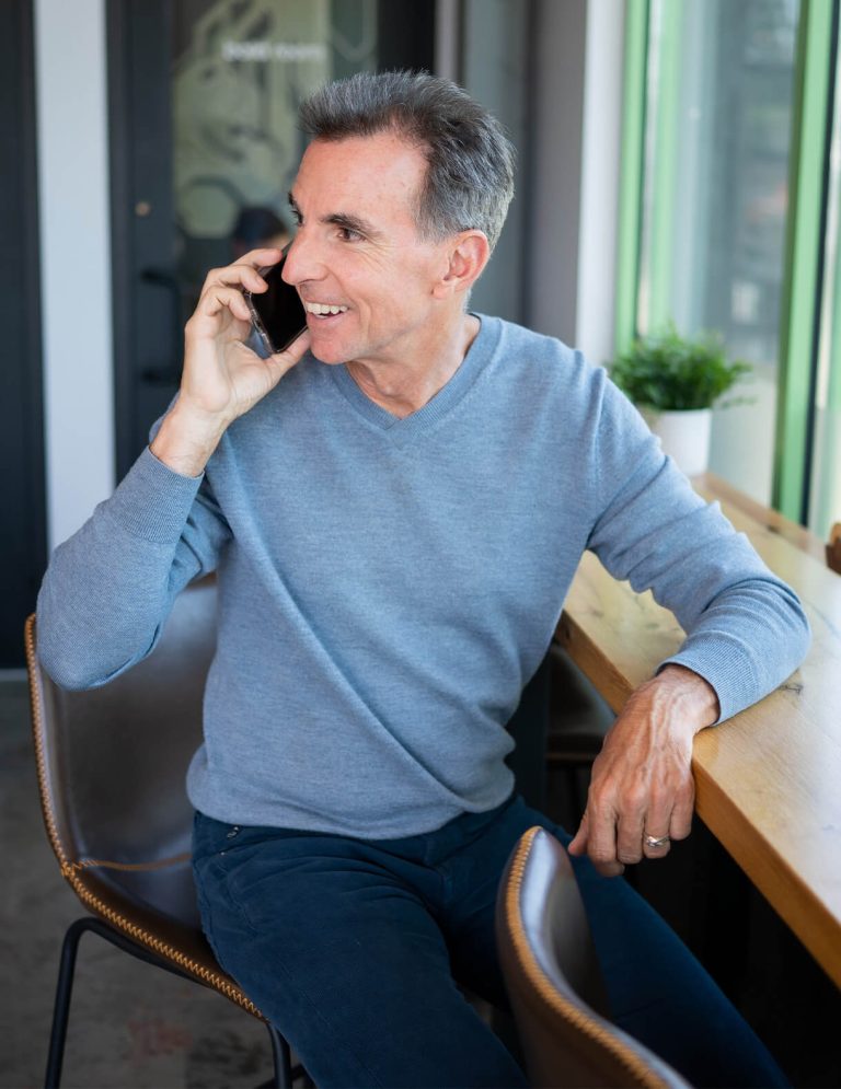 Image of Chief Marketing Officer Bob Newman in light blue sweater speaking on phone at Paradigm Digital Group offices