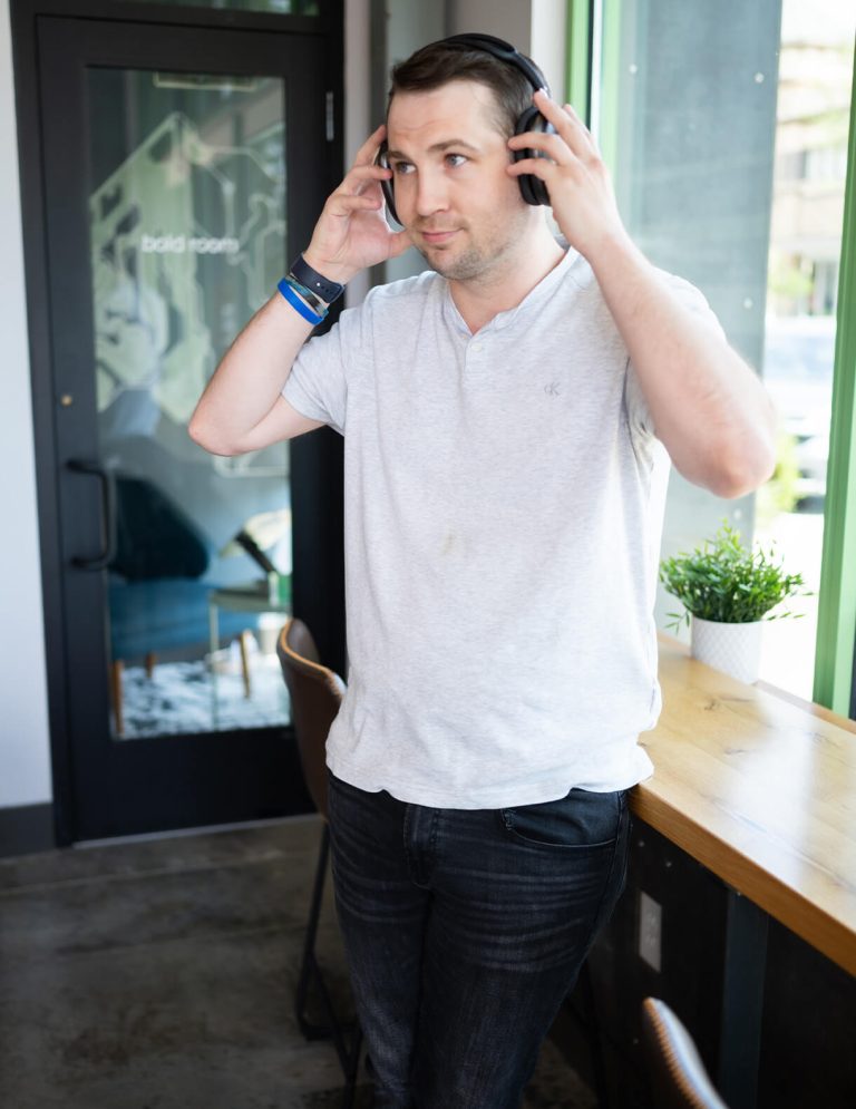 Image of Lead Video Editor Eric Knifong in light gray buttoned shirt holding on-ear headphones at Paradigm Digital Group offices