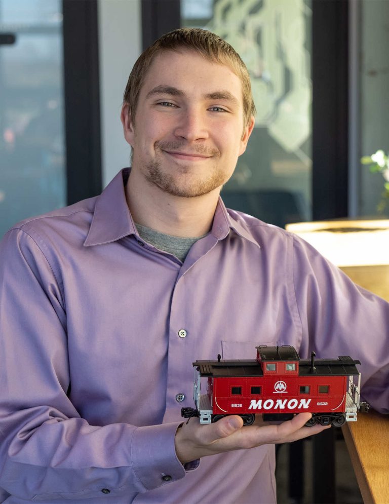 Image of Video Intern Samuel Jennings sitting and holding a model train at Paradigm Digital Group offices