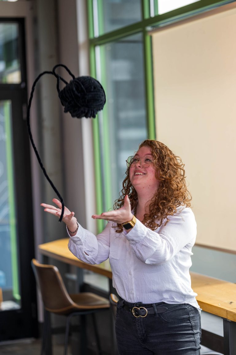 Image of Digital Marketing Specialist, Taylor Faulds, at Paradigm Digital Group throwing a yarn ball up in the air while looking up at it