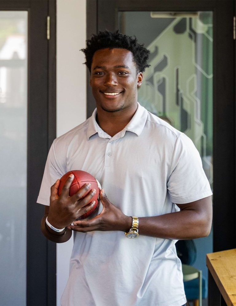 Image of Digital Content intern, Ershod Jasey II, holding a football with both hands at Paradigm Digital Group offices