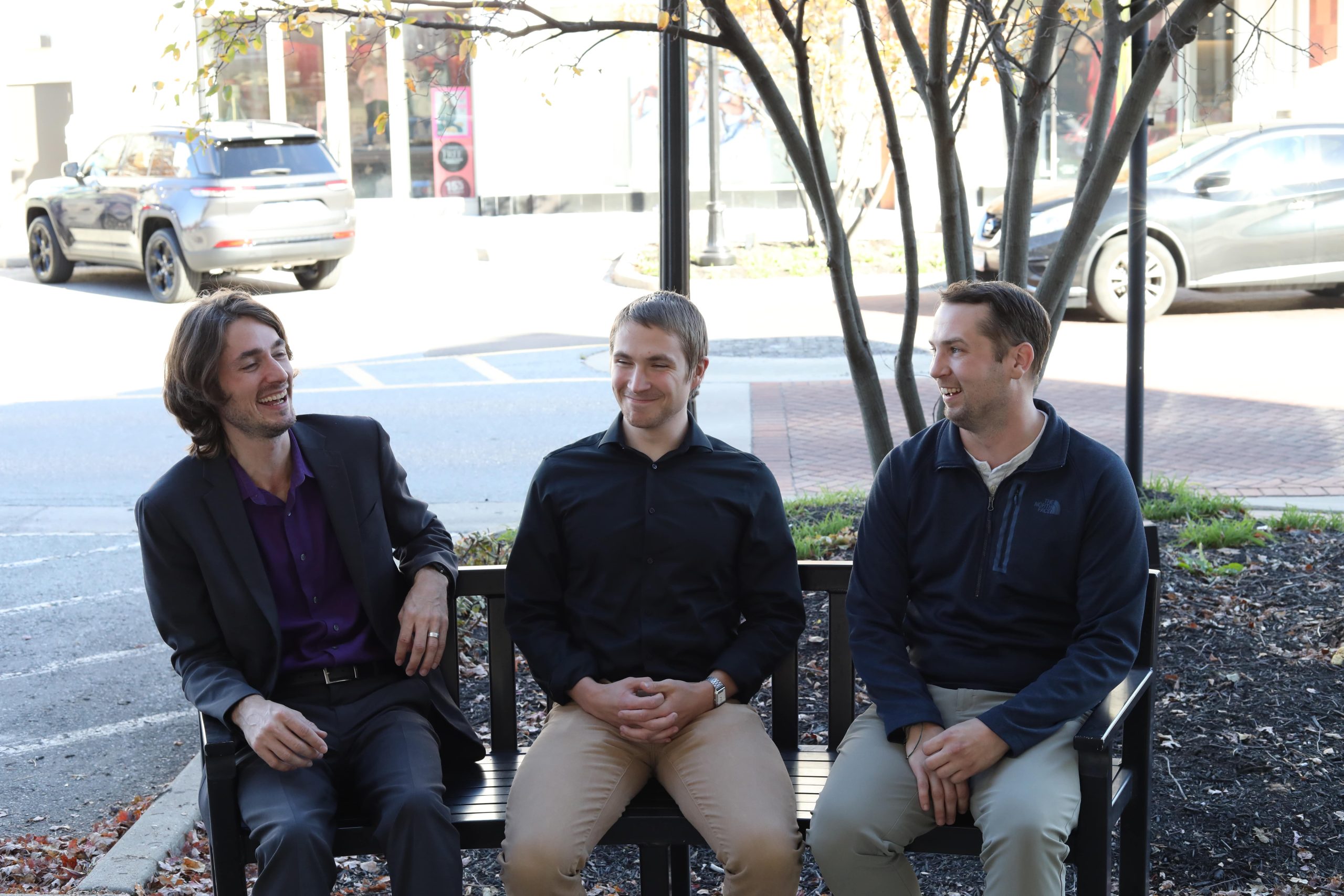 Evan, Eric, and Sam sitting on a bench, laughing and smiling
